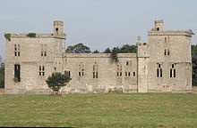 A stone building in a field, with a tower at each end.