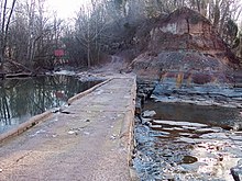 A 1947 low water bridge maintains the partial flow of Middle Island Creek (left) around the Jug. The creek emerges from the bend just to the right of the frame of the photograph.