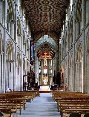 The nave of Peterborough Cathedral (1118–1193) in three stages of arcade, gallery & clerestory, typical of Norman abbey churches. The rare wooden ceiling retains its original decoration (π. 1230). Gothic arches beneath tower (π. 1350).