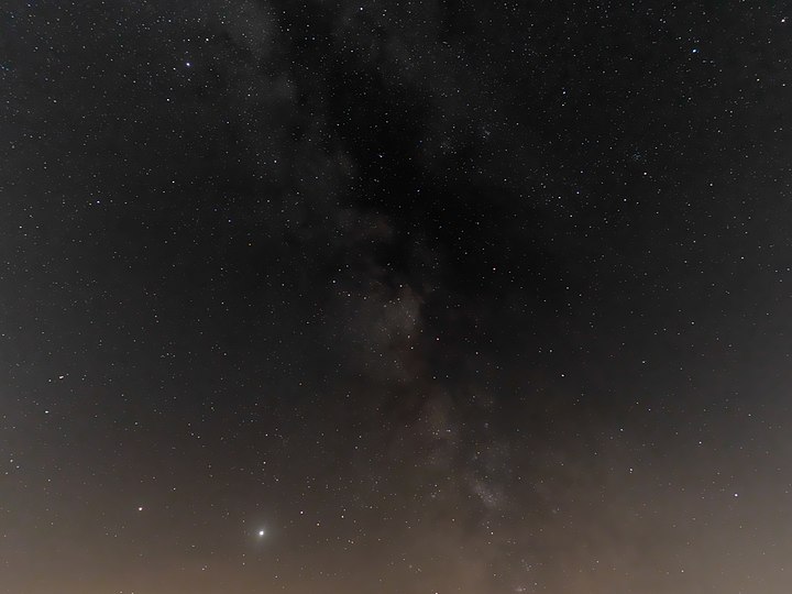 Die beiden Planeten Jupiter und Saturn im Bereich der Sommermilchstraße vom Internationalen Sternenpark Westhavelland aus gesehen. Halb links unten im Sternbild Schütze (Sagittarius) der helle Planet Jupiter (scheinbare Helligkeit = -2,5m) in einer Höhe über dem Horizont von 15 Bogengrad, links daneben der etwas dunklere Planet Saturn (scheinbare Helligkeit = 0m) in einem Abstand von rund neun Bogengrad. Oben in der Milchstraße das Sternbild Adler (Aquila).