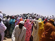 Foule de gens, dehors, sur un monticule de terre