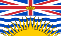 Flag with horizontally stretched Union Flag as top half. The lower half is a large yellow sun over blue and white waves.