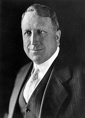 A black-and-white photograph of a middle-aged man in a business suit.