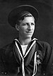 A young white man in a seaman uniform decorated with a star-shaped medal on the left breast, looking off into the distance.