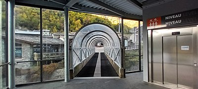 Photographie d'une passerelle couverte par un tunnel en verre.