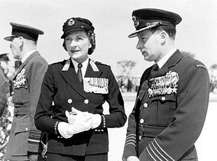 Informal outdoor portrait of man and woman both wearing dark military uniforms with medals and peaked caps