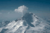 A snow-covered mountain, with a plume of steam and gas rising from the top