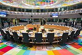 Photographie d'une salle avec un sol multicolore et des chaises disposées autour d'une table ronde.