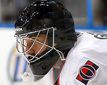 man wearing black goalie mask and hockey equipment