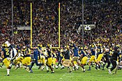 Football players and coaches running onto a football field