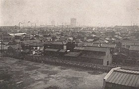 Photo d'un paysage urbain. À perte de vue sont visibles des bâtiments de deux ou trois étages, et quelques cheminées industrielles percent au loin.