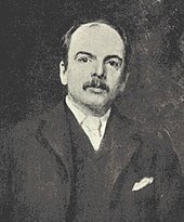 A man with a moustache and a dark suit