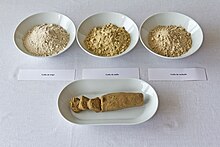 Three small bowls of flour laid out behind a loaf of bred