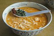 Laksa, with chilli paste and chopped laksa leaf in a spoon