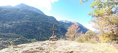 Photographie d'une croix édifiée en bois qui est sur un promontoire naturel rupestre, elle est en bois et domine la forêt adverse.