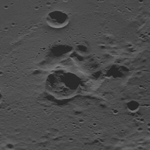 Oblique view facing east with the dark interior crater near center, showing that the dark crater is adjacent to a complex depression