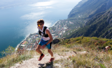 photographie d'un sportif courant sur les hauteurs montagneuse avec en arrière fond une ville au bord de l'eau