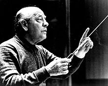 A black-and-white photograph of an older man conducting an orchestra