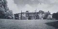 The open courtyard of a four-story manor house-style brick building with trees to the left and right