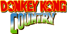 Donkey Kong Country est écrit sur deux lignes, la première avec des lettres rouges bordées de jaune et l'autre dans un double dégradé du vert clair au bleu par le blanc.