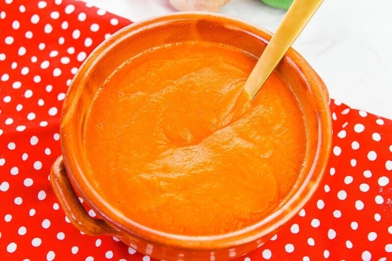 Overhead shot of roasted carrot soup on top of a red polka dot place mat.