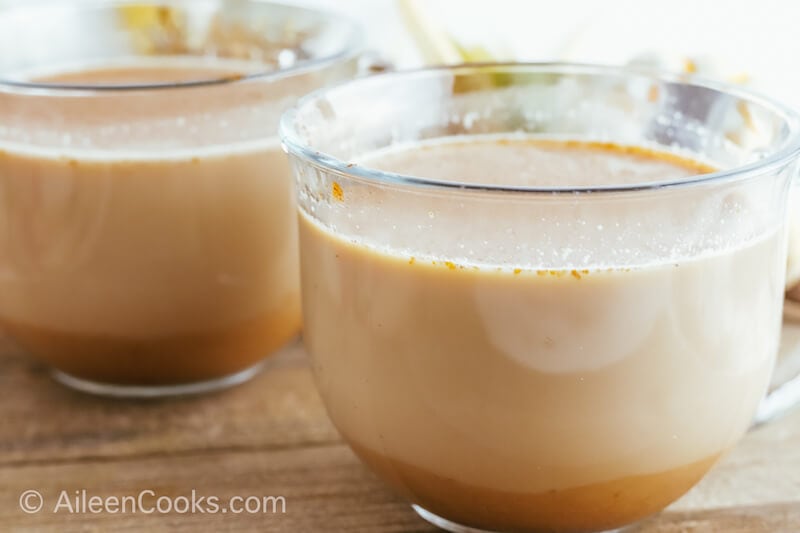 Side view of two pumpkin spice lattes in glass mugs.