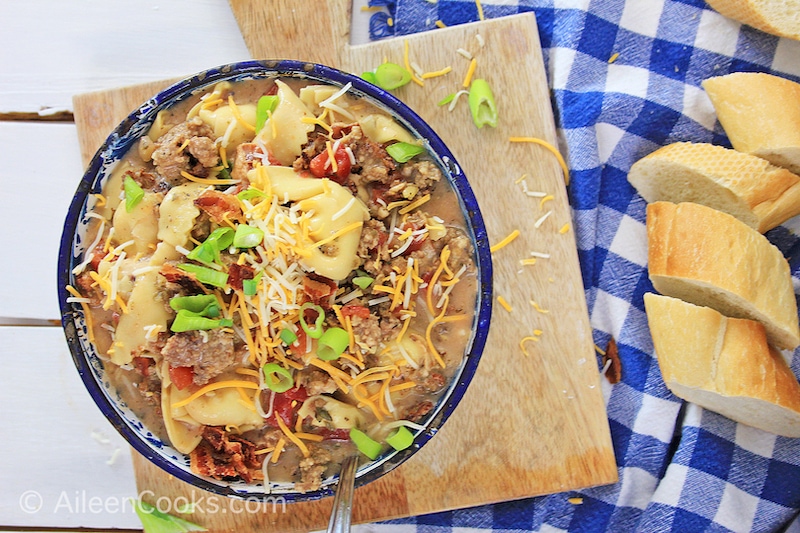 Overhead shot of instant pot tortellini soup sitting on a wooden cutting board.