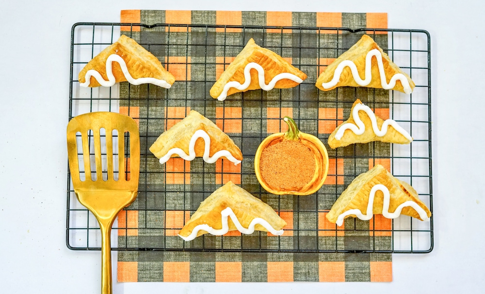 A cooling rack filled with air fried pumpkin turnovers.