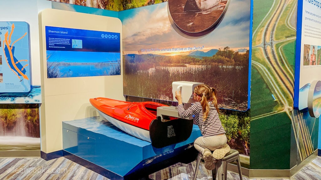 A girl looking through a viewfinder shaped like a boat.