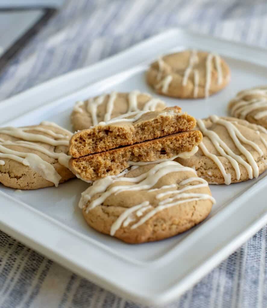 Brown sugar sourdough maple cookie broken in half and placed on a plate on top of other cookies.