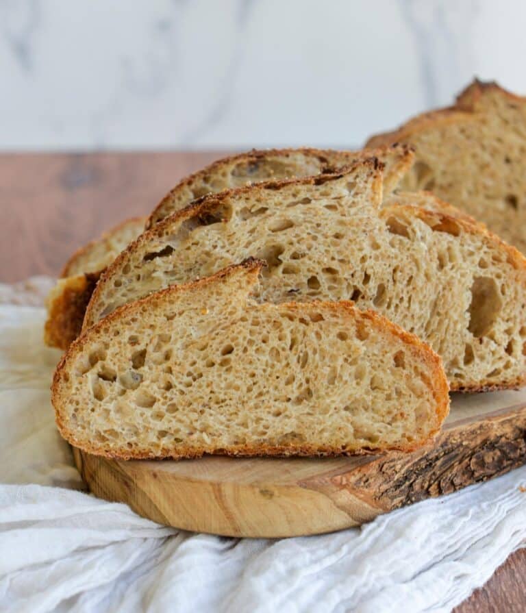 Slices of multigrain sourdough bread sitting on a wooden board.