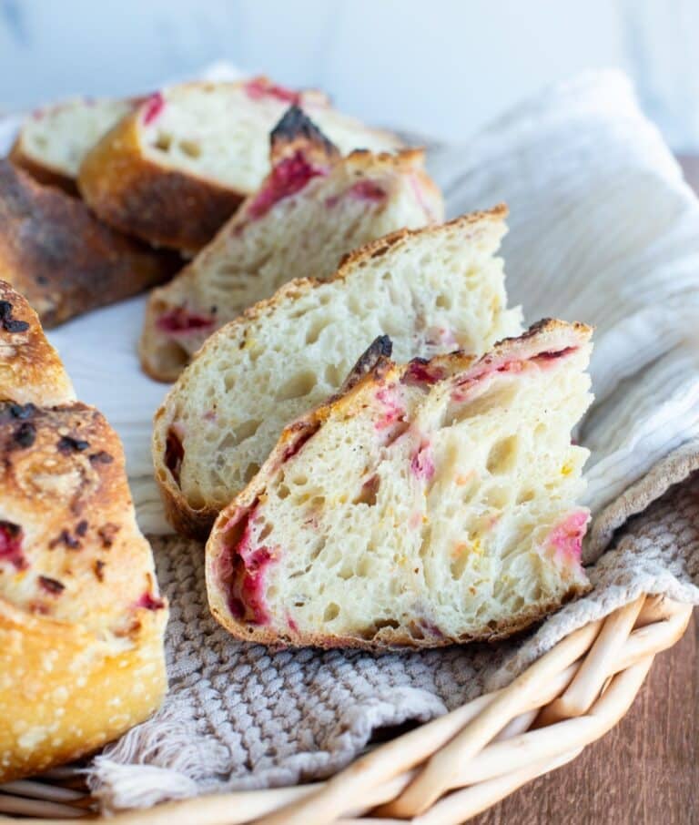 Sliced cranberry orange sourdough on a kitchen towel in a basket.