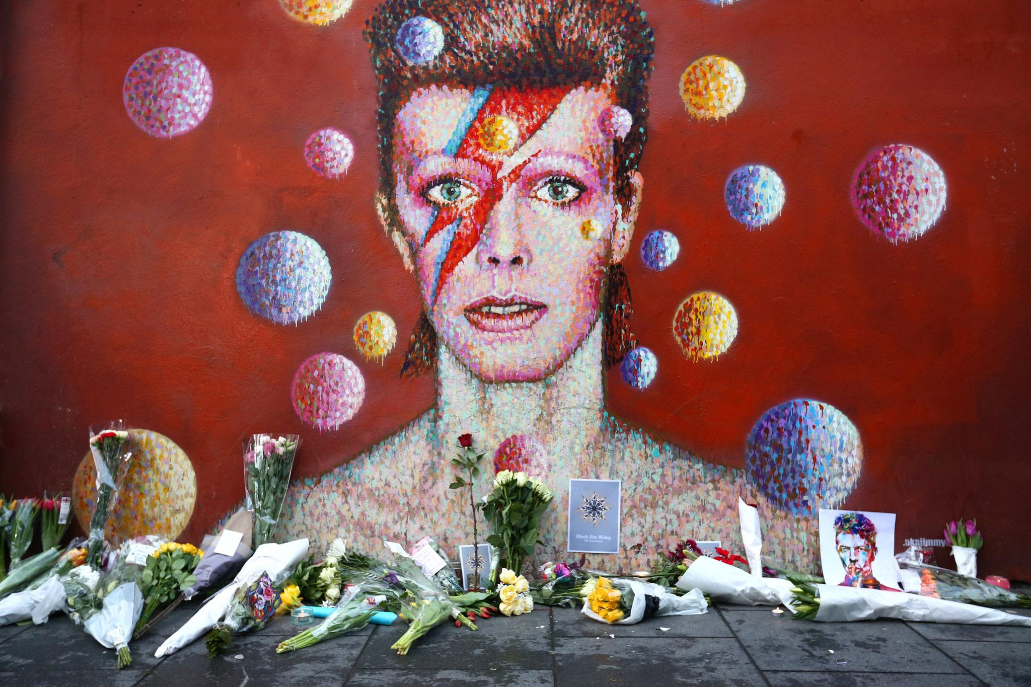 Flowers are laid beneath a mural of David Bowie in London's Brixton district on January 11, 2016. Bowie planned many posthumous album releases, Newsweek reports.