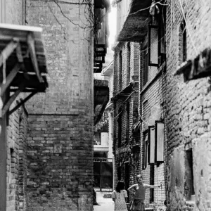 Girls standing talking in lane flanked by old brick buildings