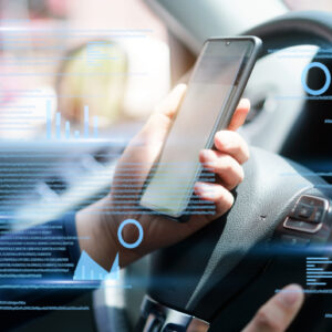 Person holding a phone over a steering wheel in a car, with blue data points and charts overlaid.