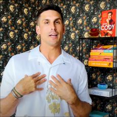 Cody rigsby standing in front of his bookshelf 