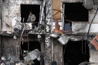 Daniel Leal photo of Ukrainian serviceman is seen in the window of a damaged residential building Kyiv