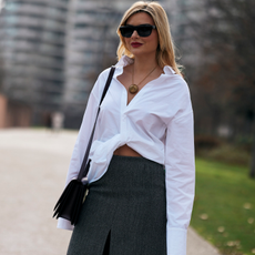 A guest attends the milan fashion week spring summer 2024 in a white button down, grey skirt, black sunglasses, and crossbody bag