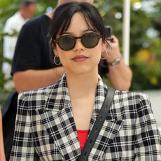 Jenna Ortega wearing a plaid blazer, a red top, and sunglasses 