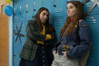 Beanie Feldstein crosses her arms and wears a plaid blazer next to a friend in the movie 'Booksmart'