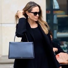 Angelina Jolie wears a celine bag black coat and drop earring while running errands