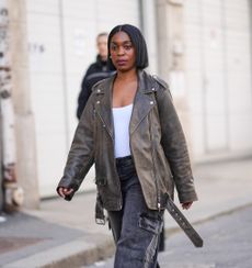 Woman wearing white tank, leather jacket, and denim