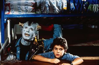 Howie Mendel sits next to Fred Savage while dressed like a blue monster