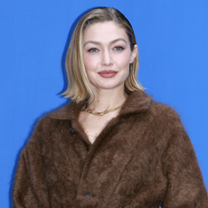 Gigi Hadid poses for media during the "Guest In Residence" Seoul pop-up store opening at Tom Greyhound on November 04, 2024 in Seoul, South Korea wearing a brown wrap coat and loafers