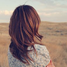 Woman with red hair wearing a floral dress staring into the distance