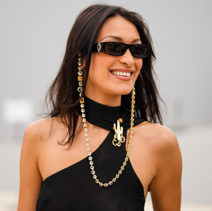 Bella Hadid wears sunglasses with a bejeweled / diamonds chain, a black off-shoulder cropped top with turtleneck, outside Dior, during Paris Fashion Week - Menswear Spring/Summer 2022, on June 25, 2021 in Paris, France. 