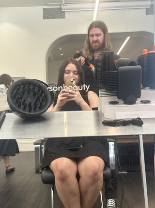 Brooke knappenberger marie claire editor sitting in hair salon chair with dyson global hair stylist matthew collins using the dyson airwrap on her hair and dyson attachments