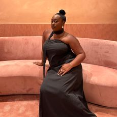 Fashion editor posing in pink room wearing gray dress and neck scarf