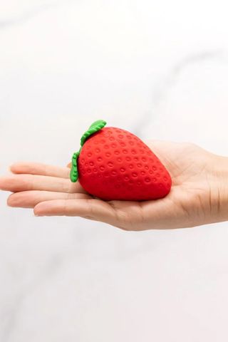 small, strawberry-shaped sex toy in the palm of someone's hand