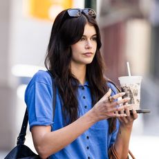 Kaia Gerber wearing a blue short-sleeve sweater, black pants, and ballet flats with two maxi bags for MDW in New York City May 2024